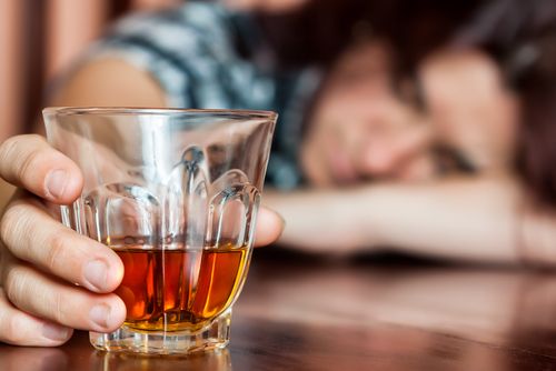 woman passed out drunk on table holding drink