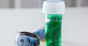 marijuana in medicine bottle next to bong on table
