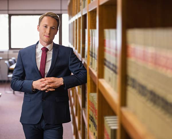 attorney standing next to law books on shelf