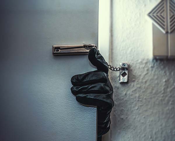 Burglar with glove on opening a locked door